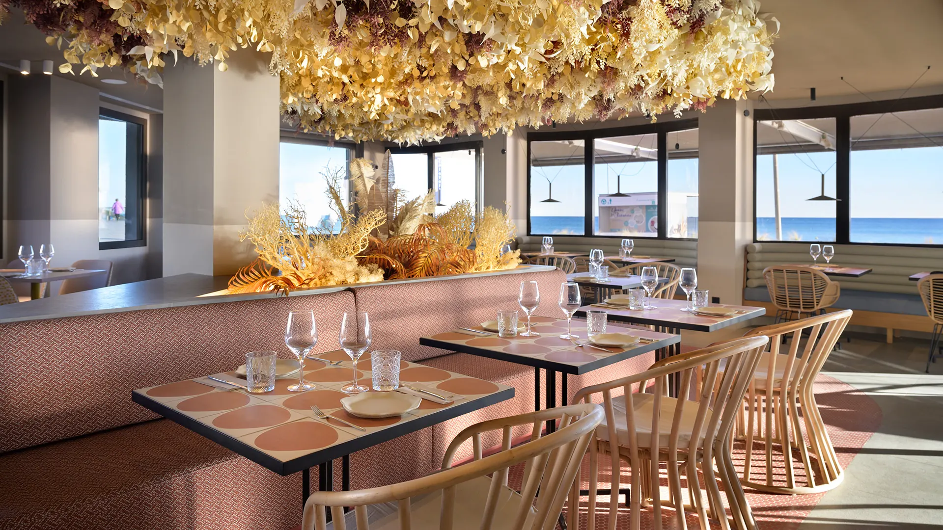 Sala del Restaurante Akquaaa en Calafell, con la instalación de flores secas en el techo y los ventanales al mar