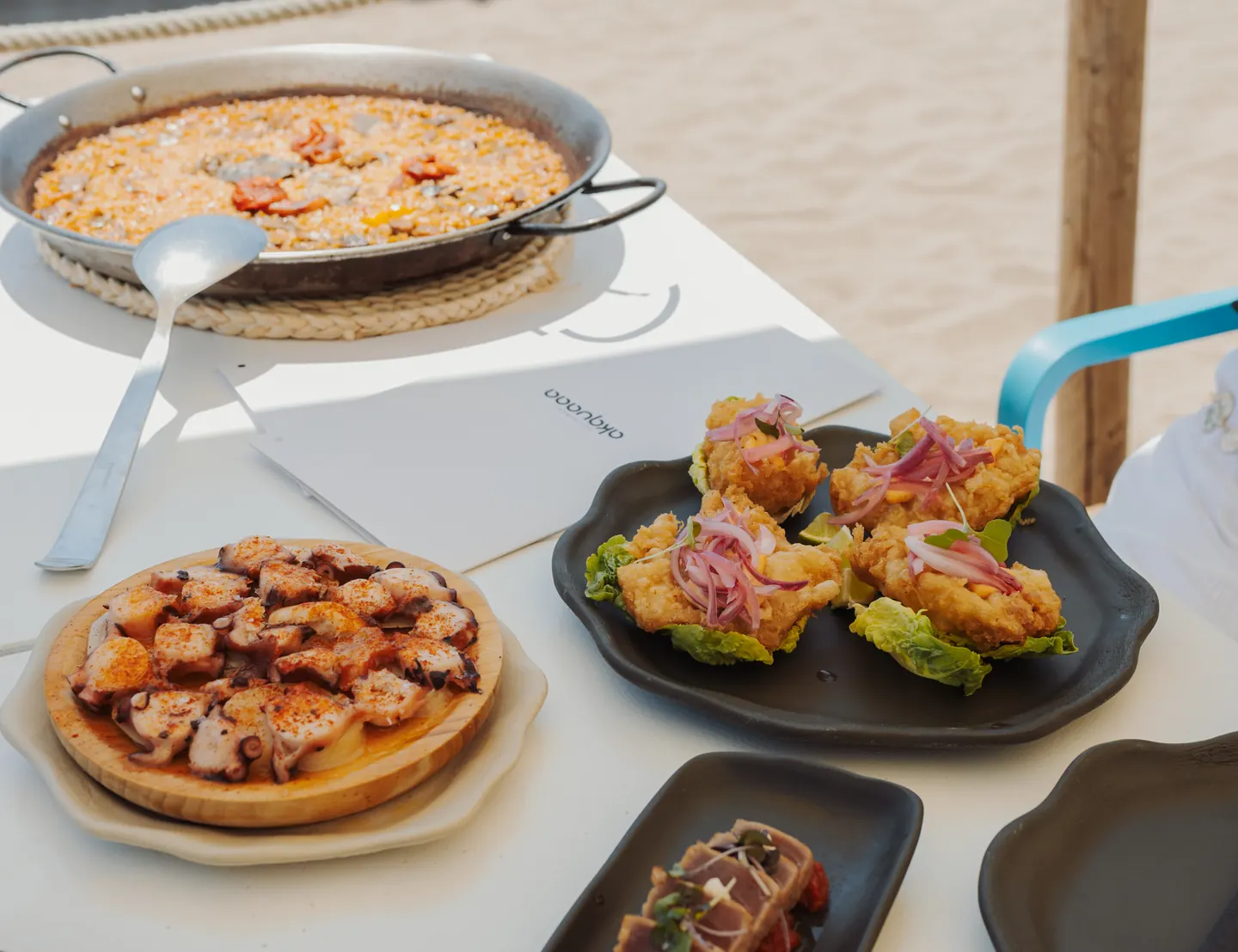 Mesa de la terraza de Akquaaa con arroz y picoteo frente al mar de Calafell